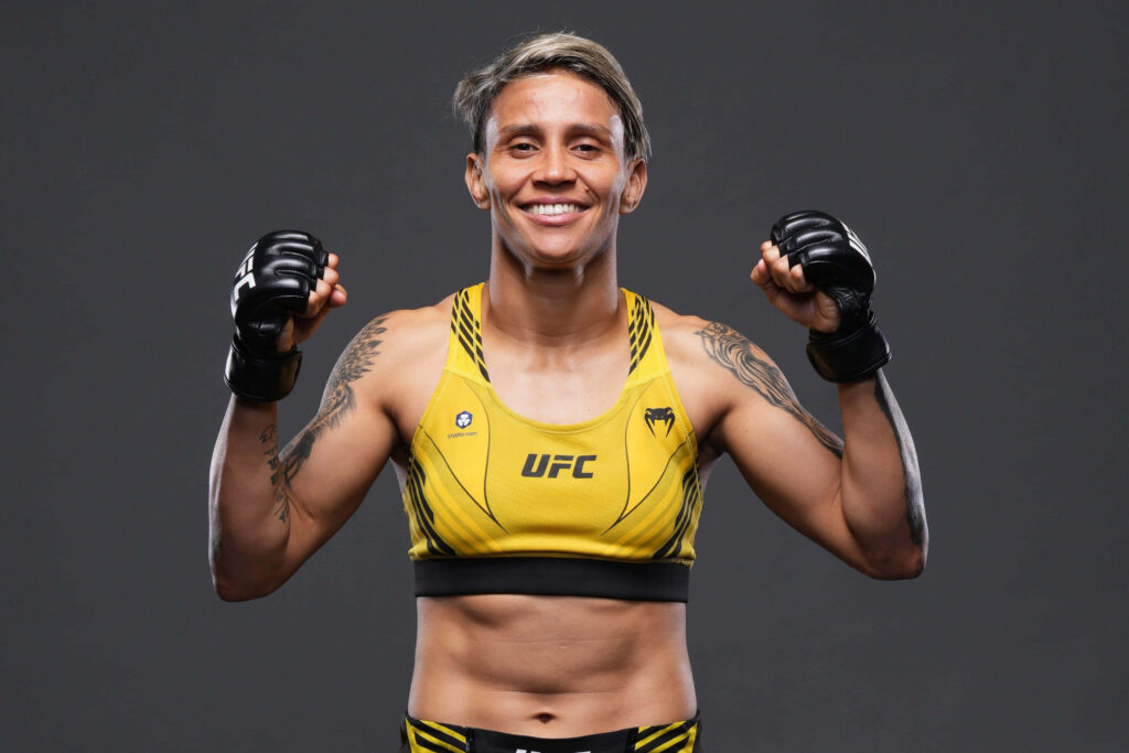 Amanda Lemos UFC fighter in fight gear smiling confidently against neutral wallpaper background