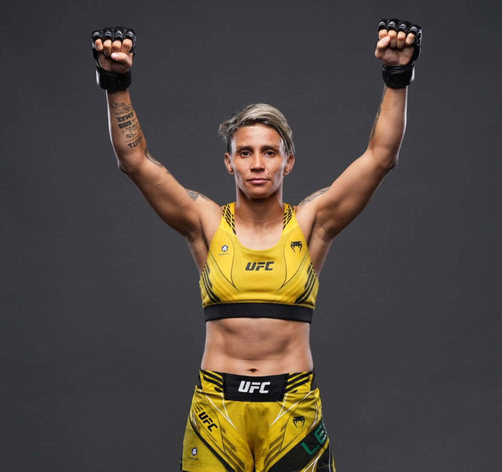 Amanda Lemos UFC fighter victorious pose strength determination in fight gear on plain background Wallpaper