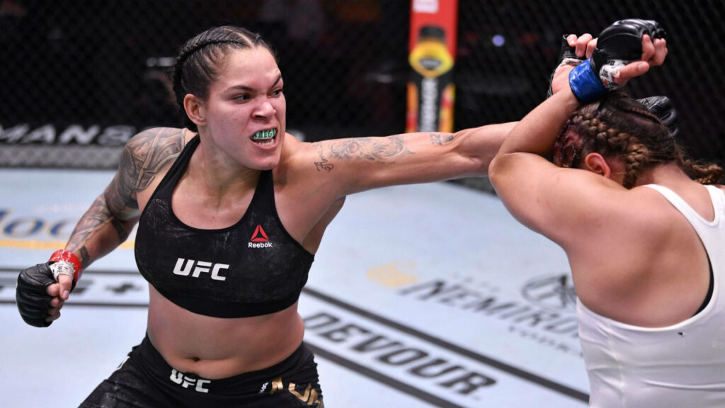 Amanda Nunes MMA fighter unleashing fierce punch in octagon intense mixed martial arts fight Wallpaper