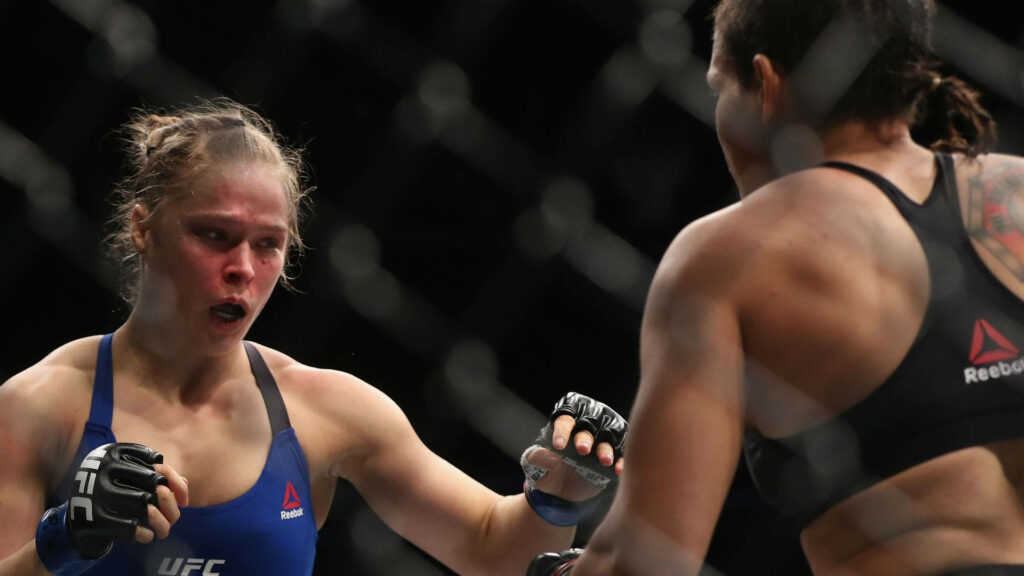 Amanda Nunes dominating UFC octagon fight showing strength determination intense battle wallpaper background