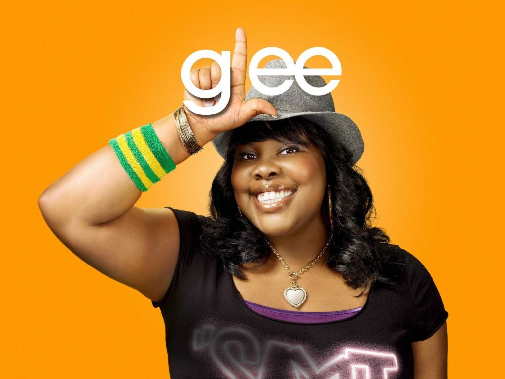 Amber Riley as Mercedes Jones on orange background striking iconic L pose Glee wallpaper