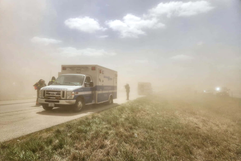 Ambulance on dusty rural road with emergency responders in stormy weather background wallpaper