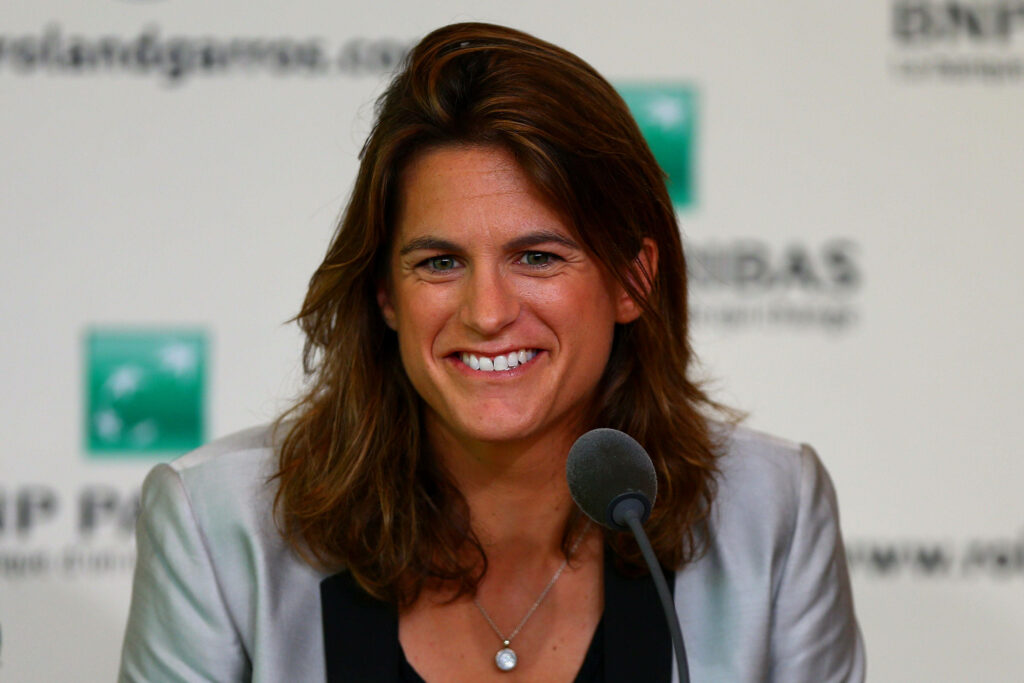 Amélie Mauresmo smiling confidently at Roland Garros press conference in professional attire Wallpaper