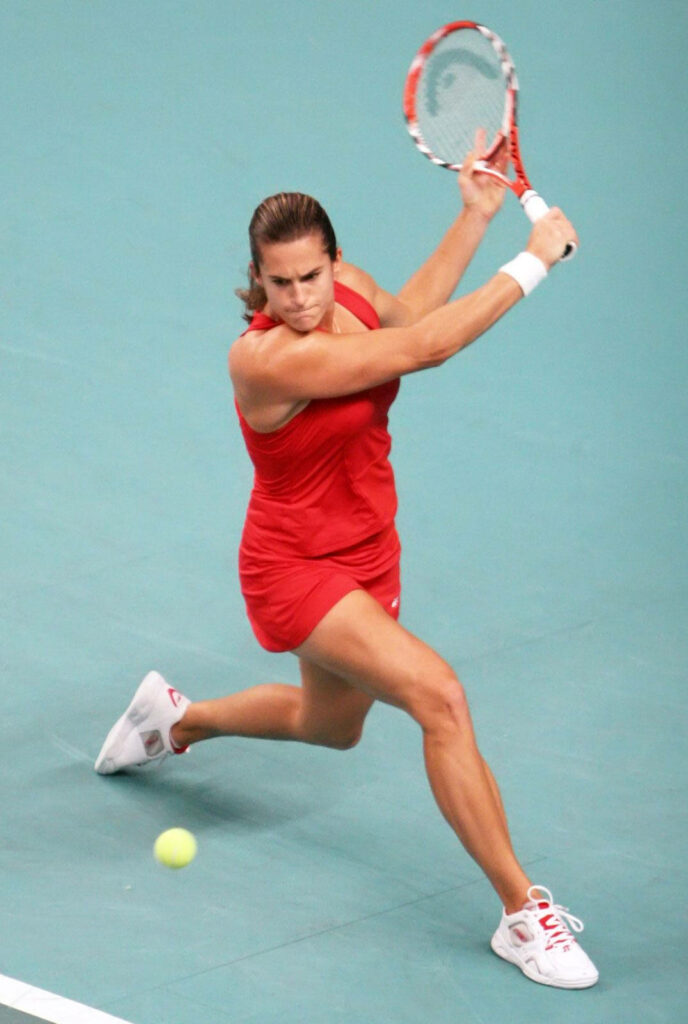 Amélie Mauresmo intense tennis backhand stroke action on court with wallpaper background