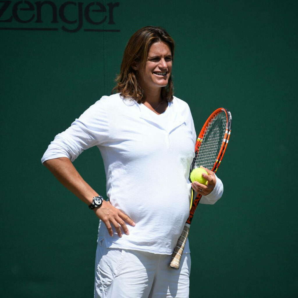 Amélie Mauresmo in white watching tennis match holding racket and ball with focused calm look Wallpaper