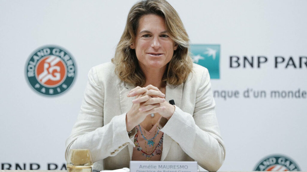 Amélie Mauresmo seated in light blazer at Roland Garros press event with BNP Paribas logos background Wallpaper
