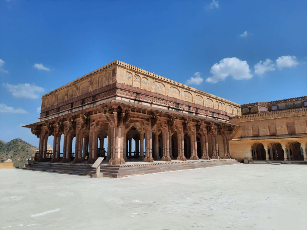 Amer Fort under clear blue sky showcasing intricate architecture and grand sunlit columns Wallpaper