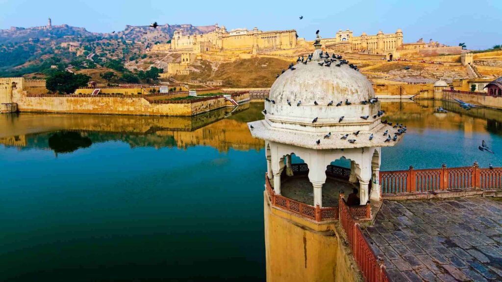 Amer Fort reflected in calm lake with detailed pavilion in foreground scenic wallpaper background