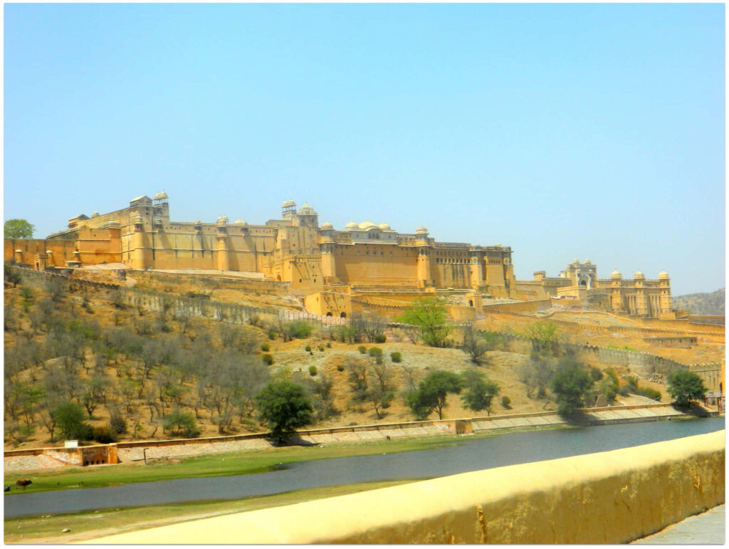 Amer Fort on rugged hilltop with yellow sandstone walls under clear blue sky wallpaper background