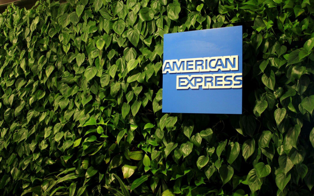 American Express logo on lush green leafy plant background vibrant corporate nature wallpaper