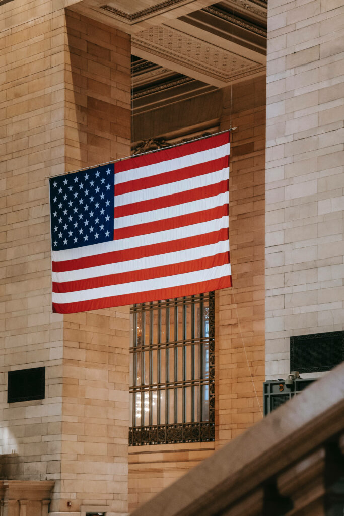 Large American Flag hanging inside historic Grand Central Terminal showcasing patriotic decor Wallpaper