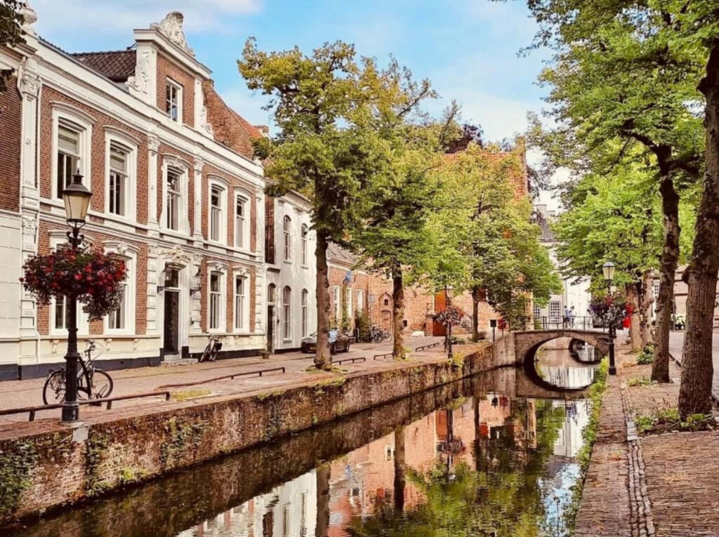 Amersfoort canal street with historic buildings tree-lined walkways and tranquil water reflection Wallpaper