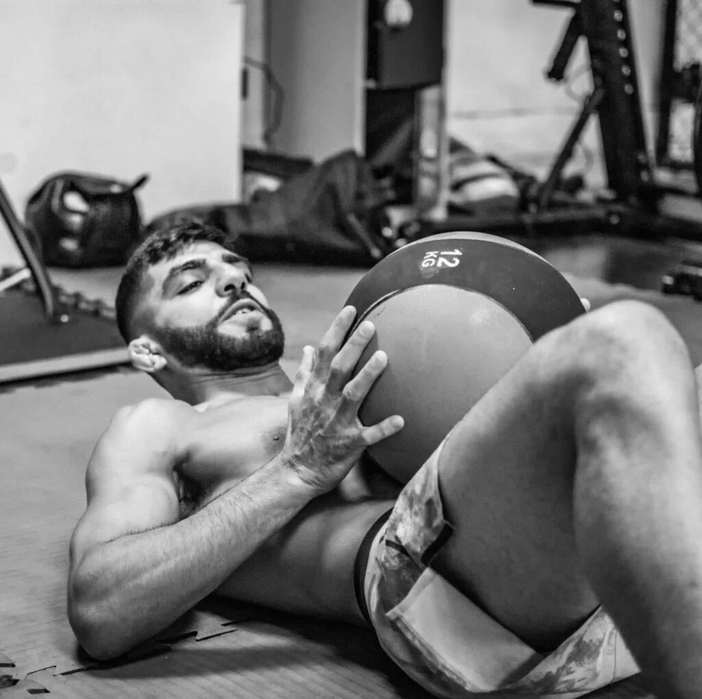 Amir Albazi training core strength with medicine ball in gym intense workout wallpaper background