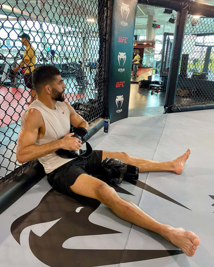 Amir Albazi resting against octagon fence after intense UFC training session showing focus Wallpaper