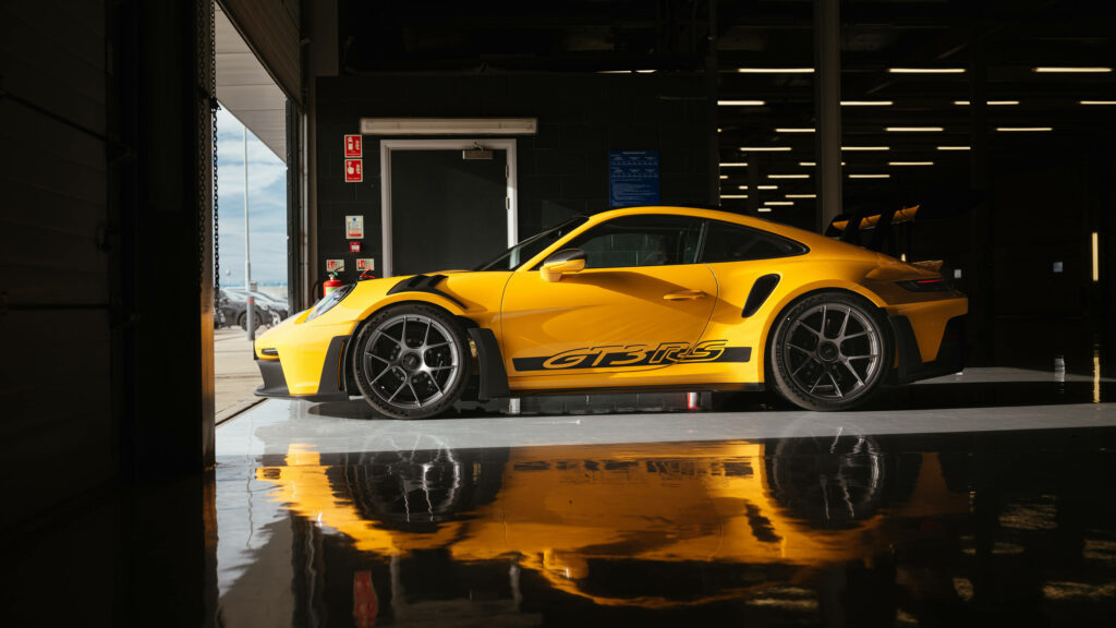 Yellow Thunder: A Picture-Perfect GT3 Porsche Car Resides Inside A Garage With Glossy Floors - An Ideal 5120x1440 Wallpaper for Auto Enthusiasts!