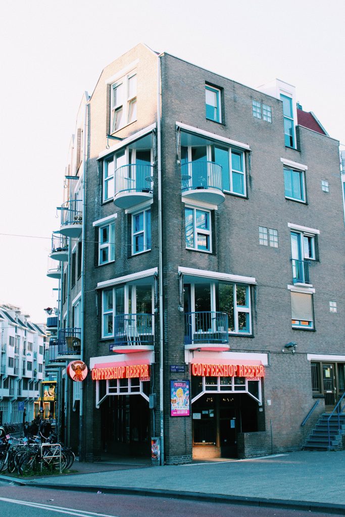 Coffeeshop Reefer Amsterdam brick building blue balconies neon sign urban coffee shop wallpaper