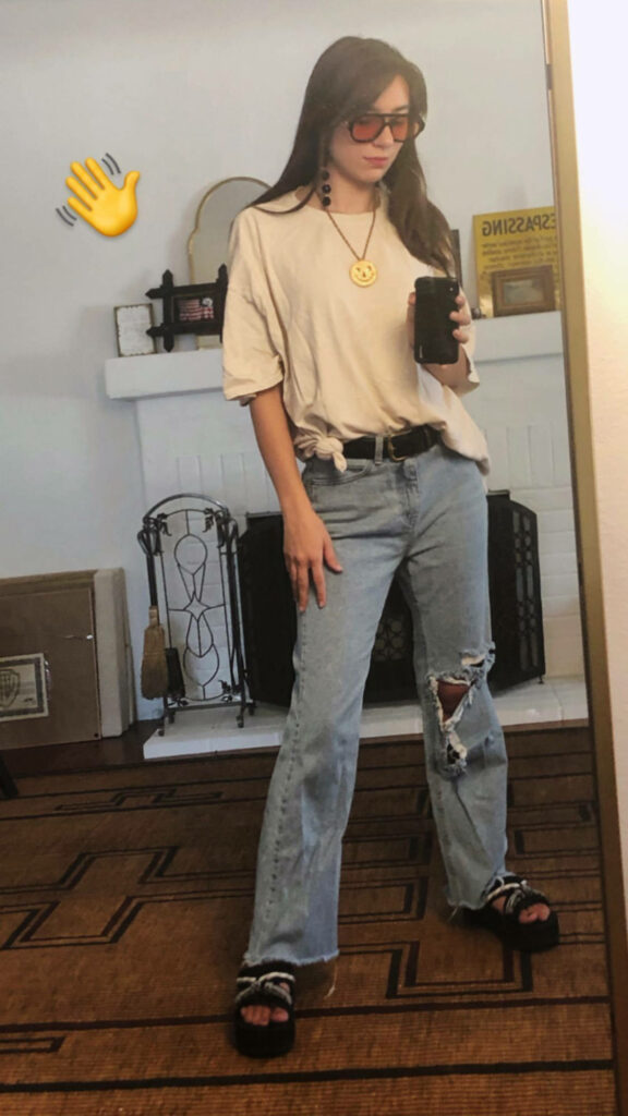 Amy Nelson stylishly posing in casual cream top ripped jeans and trendy sandals mirror background Wallpaper