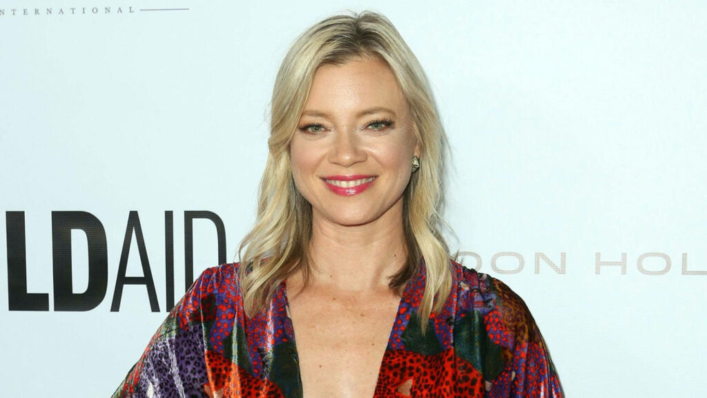 Amy Smart smiling in vibrant colorful robe against light background elegant wallpaper image