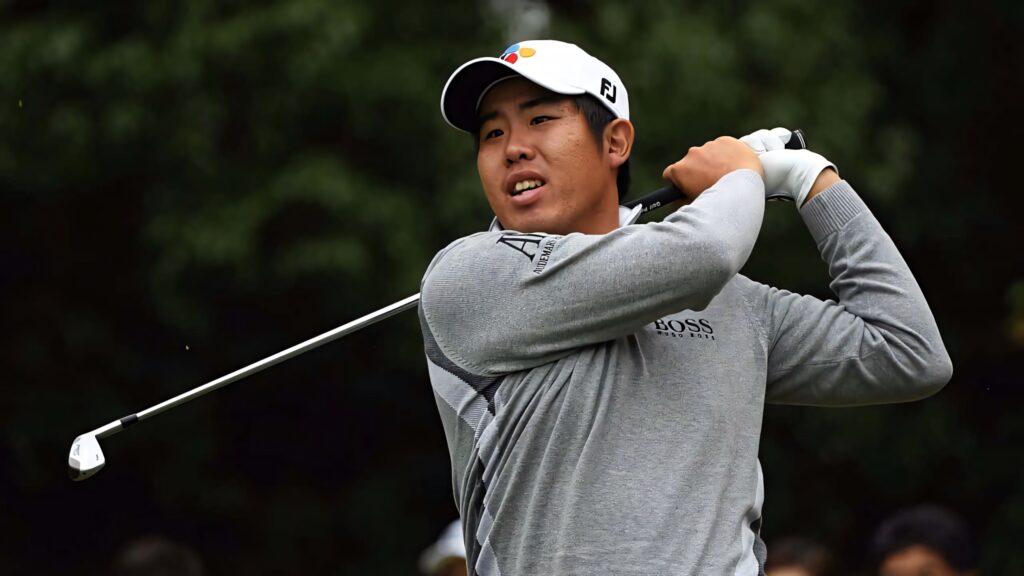 An Byeong-hun mid-swing on golf course wearing gray polo and white cap with green background Wallpaper