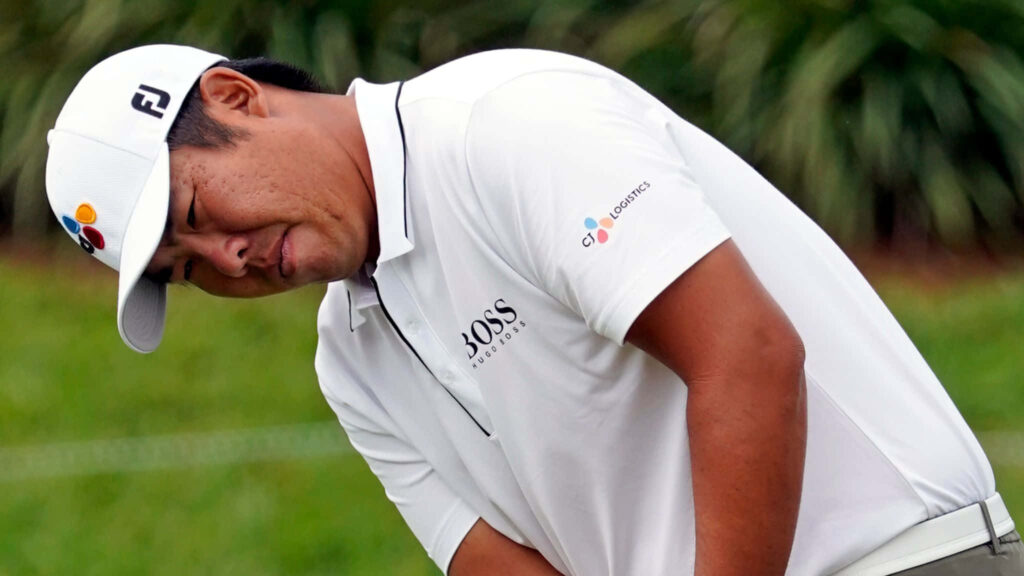 An Byeong-hun focused golf swing in white shirt and cap amid lush green golf course background Wallpaper