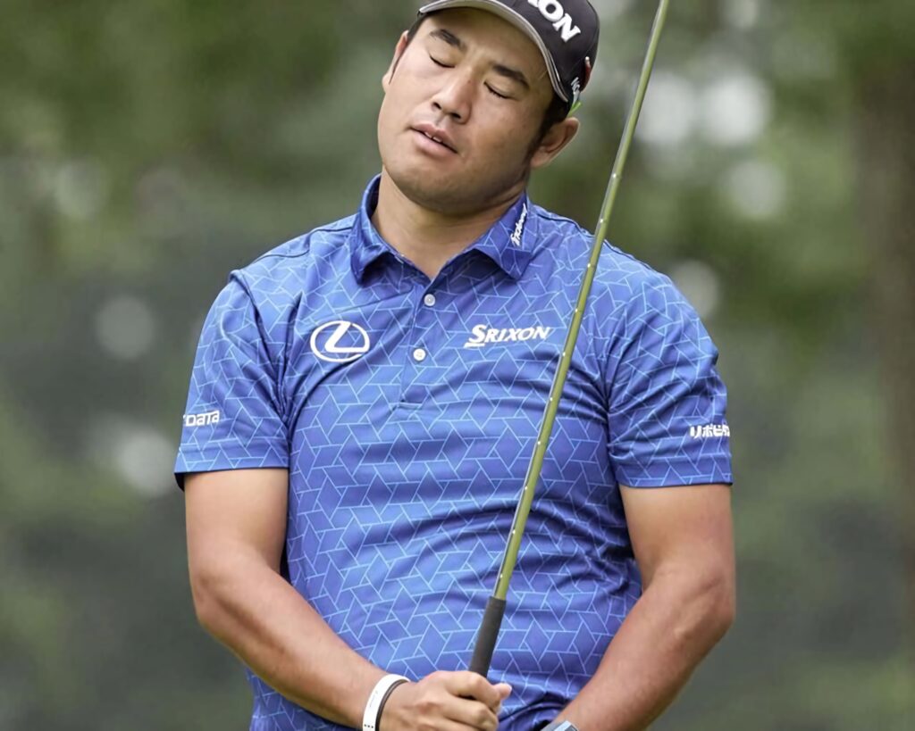 An Byeong-hun mid-swing in blue geometric shirt focused in competitive golf with green background Wallpaper