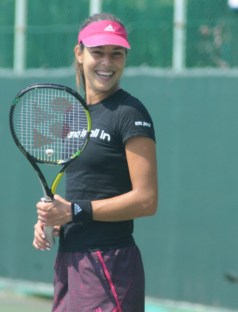 Ana Ivanović smiling with tennis racquet in hand showing love for tennis in crowded background Wallpaper