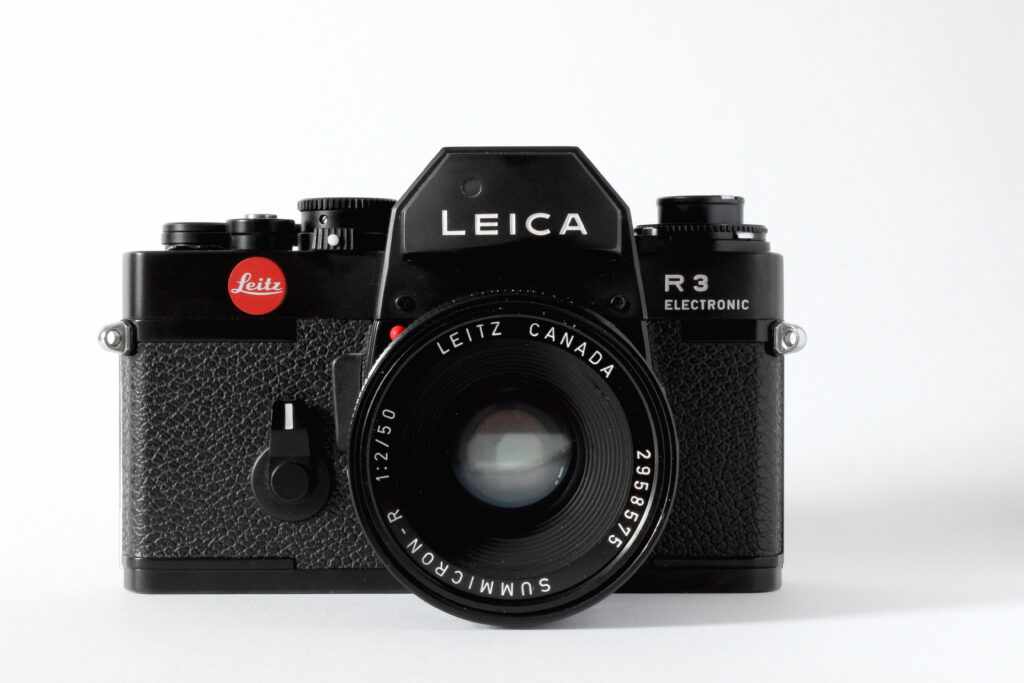 Black Leica R3 film SLR camera with Summicron-R 50mm lens on white background wallpaper