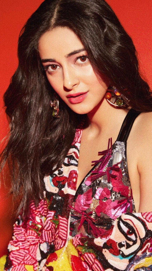 Ananya Pandey in vibrant patterned outfit posing confidently against bold red background Wallpaper