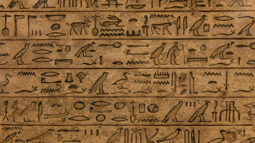 Egyptian hieroglyphic wallpaper with ancient symbols on textured stone in warm sandy tones