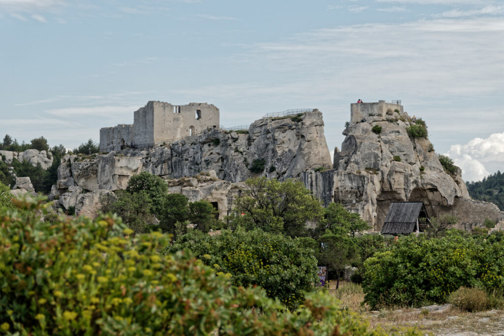 Ancient stone ruins on rocky cliffs surrounded by lush trees under a partly cloudy sky wallpaper