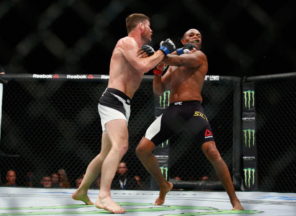 Anderson Silva receiving powerful punch in MMA octagon fight intense action wallpaper background