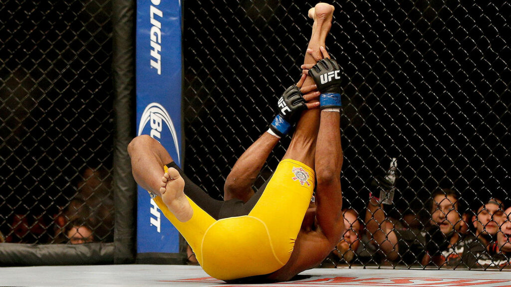 Anderson Silva holds his knee on the UFC octagon floor during intense fight moment wallpaper