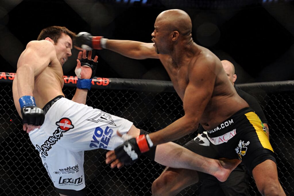 Anderson Silva delivers powerful kick dodging punch in intense MMA fight inside the octagon wallpaper