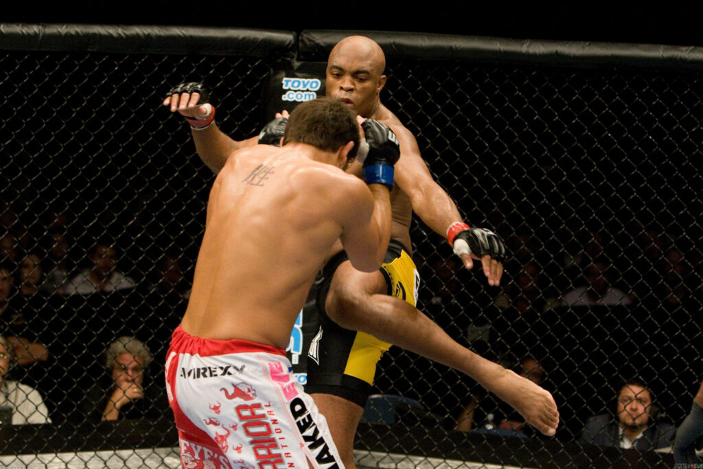 Anderson Silva delivering a powerful MMA kick in the octagon showcasing striking skills wallpaper