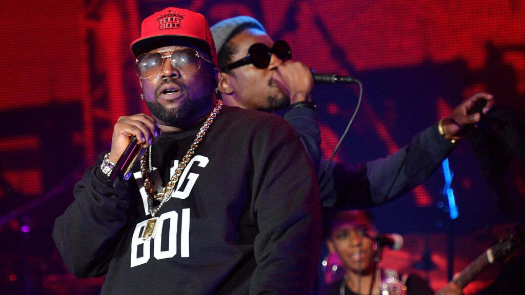 André 3000 and Big Boi performing live on stage with vibrant red concert background wallpaper