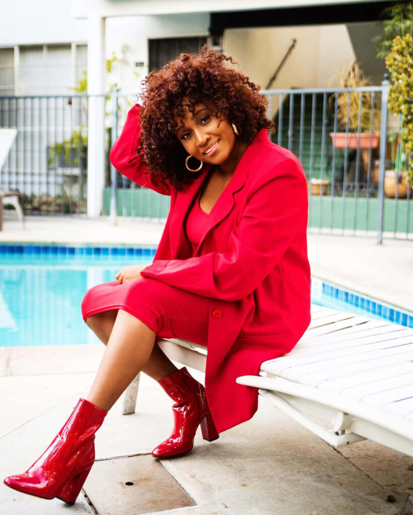 Andrea Lewis in chic red outfit sitting poolside confident stylish wallpaper background