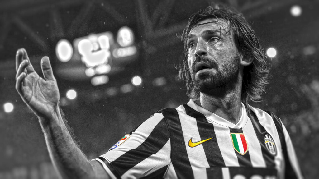 Andrea Pirlo in iconic Juventus jersey with vibrant badges against black and white stadium background Wallpaper