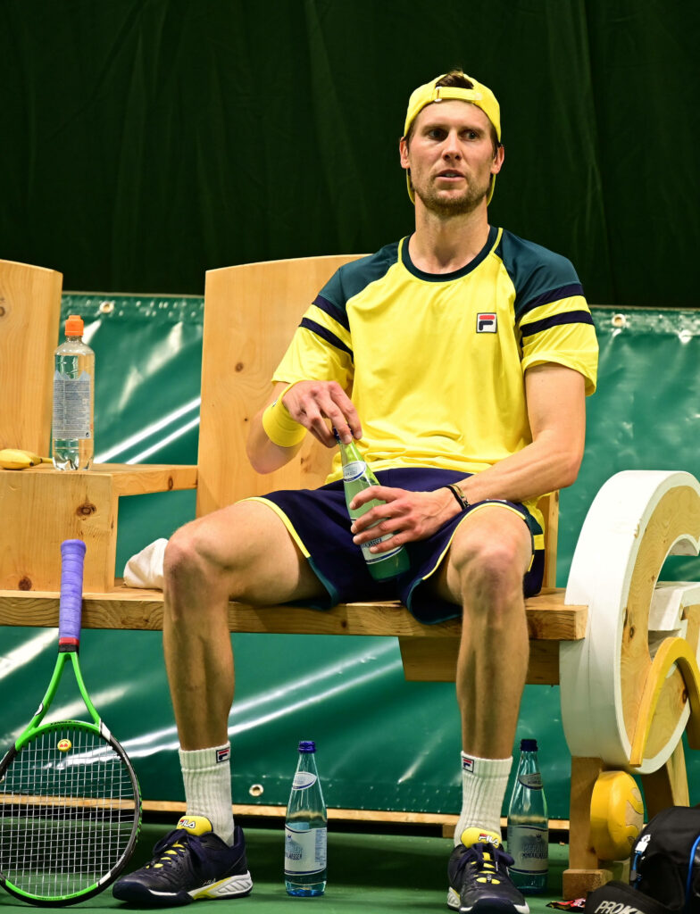 Andreas Seppi in yellow blue sportswear sitting on bench during tennis break with gear nearby Wallpaper
