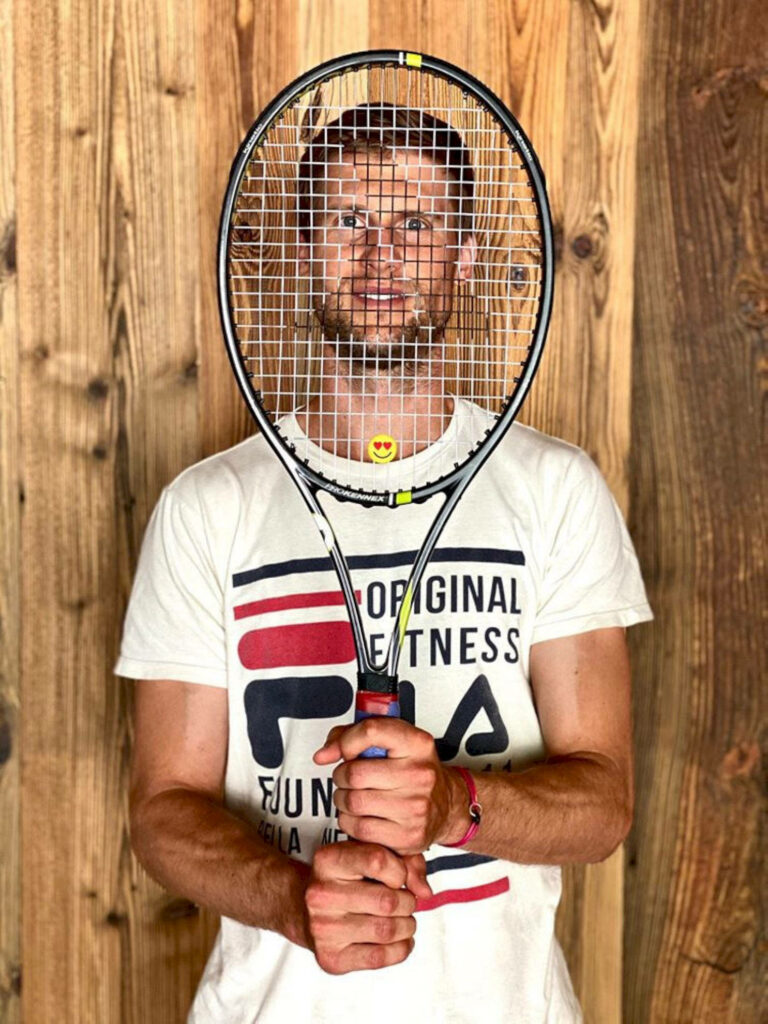 Andreas Seppi peeks through tennis racket strings smiling with wooden background wallpaper