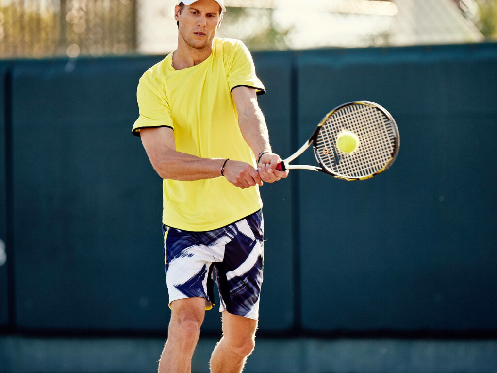 Andreas Seppi in yellow shirt hitting powerful backhand shot during intense tennis match action Wallpaper
