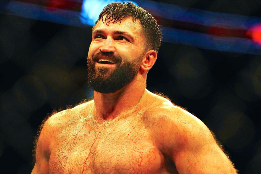Ultimate Fighting Champion Andrei Arlovski focused in arena spotlight showcasing athletic physique Wallpaper