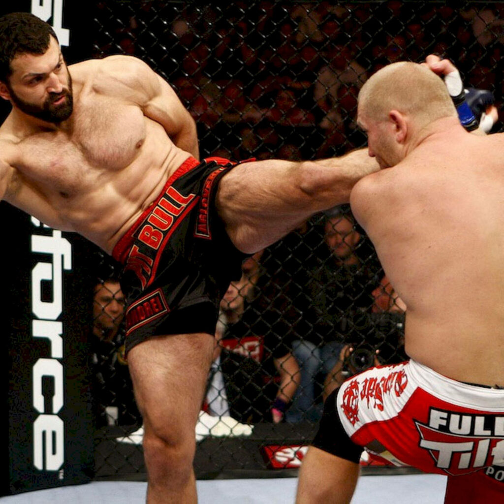Andrei Arlovski and Alistair Overeem intense MMA fight powerful kick inside cage wallpaper background