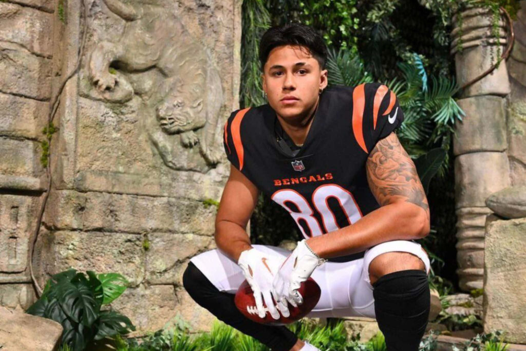 Andrei Iosivas in Cincinnati Bengals uniform holding football in jungle ruins with greenery wallpaper