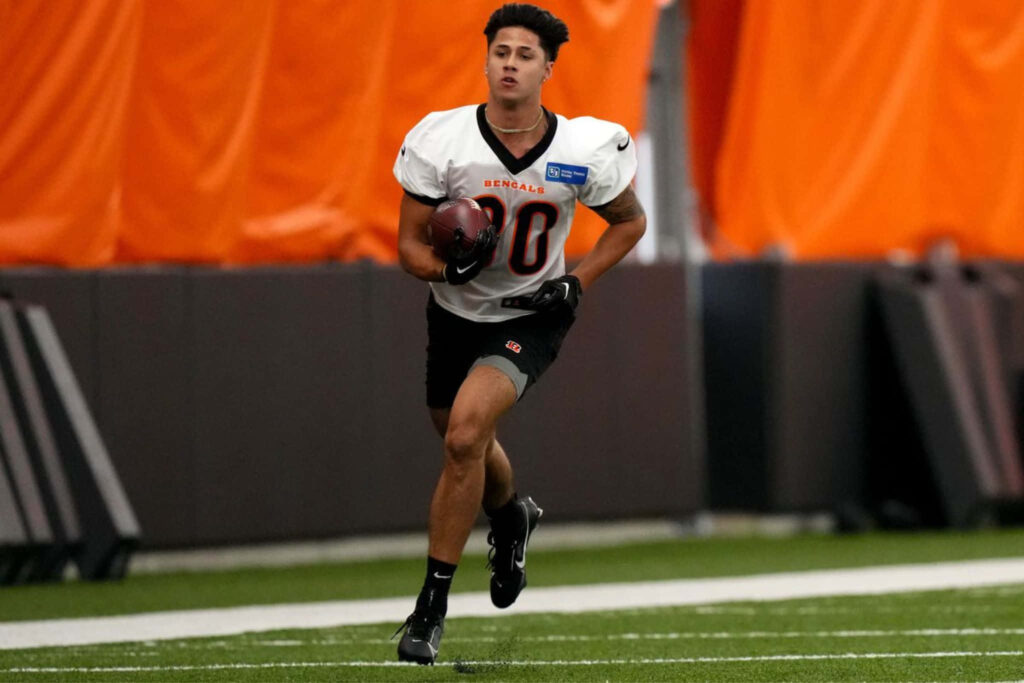 Andrei Iosivas running with football during dynamic training session on vibrant field background Wallpaper