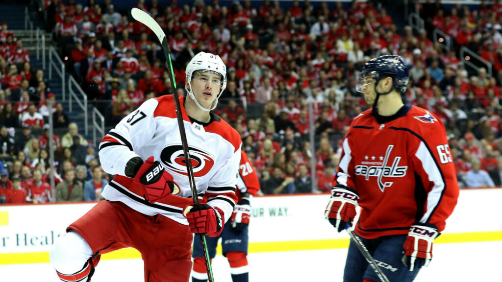 Andrei Svechnikov skating past Washington Capitals defender in intense packed arena game action Wallpaper