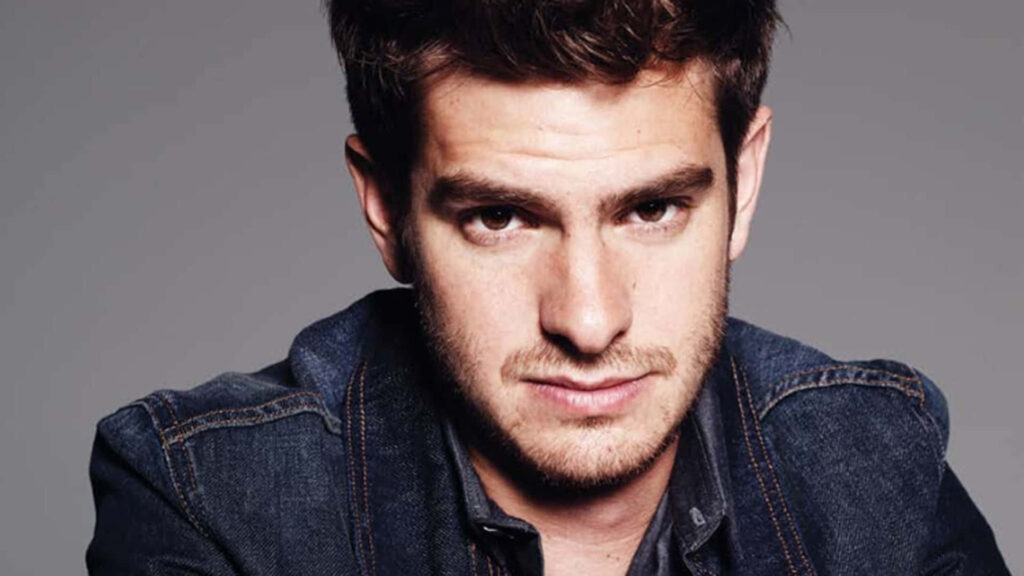 Andrew Garfield confident pose denim jacket neutral wallpaper background close up portrait
