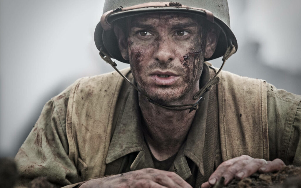 Andrew Garfield as courageous soldier in intense gritty Hacksaw Ridge battlefield wallpaper background