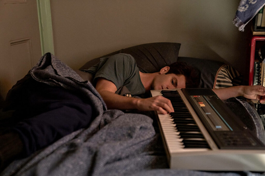 Andrew Garfield lying on bed playing keyboard creating calm creative atmosphere wallpaper