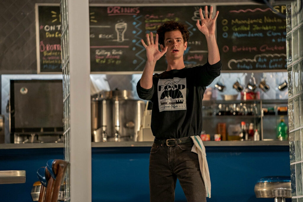 Andrew Garfield as Jonathan Larson passionately gesturing in diner scene from Tick Tick Boom wallpaper