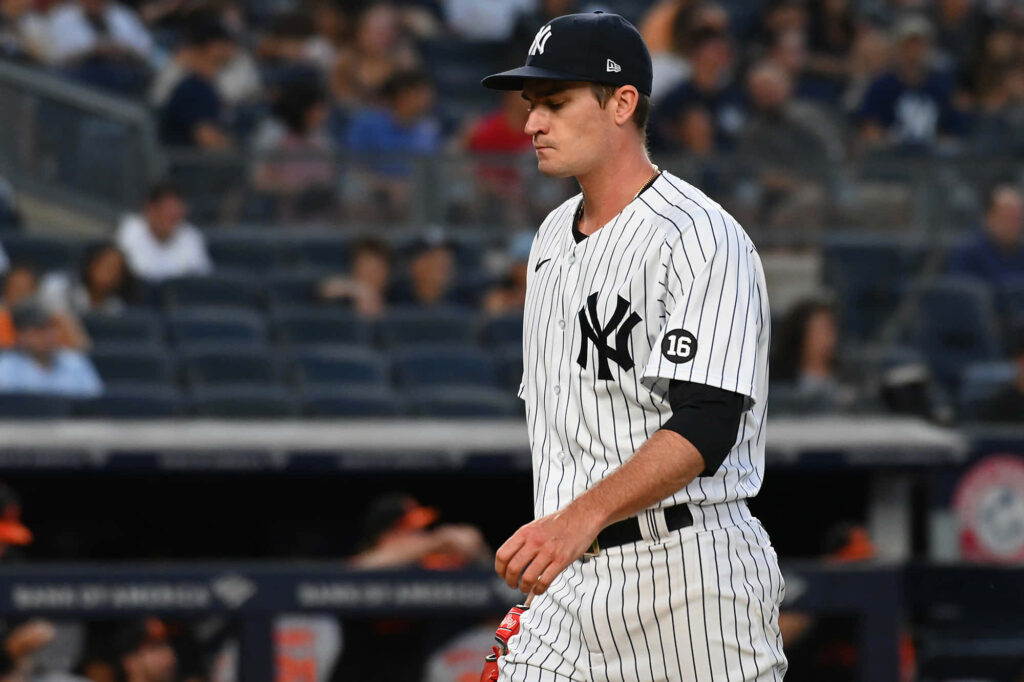 Andrew Heaney pitching in New York Yankees uniform with blurred stadium crowd in background Wallpaper